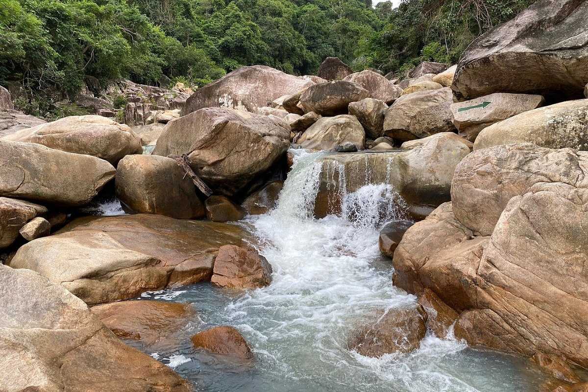 Natural stream flowing through massive boulders at Ba Ho waterfall during the coastal biking and trekking tour.