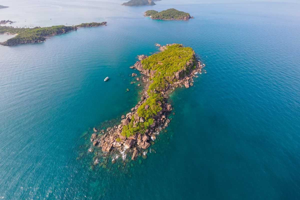 Drone view of Buom Island's rocky shores and clear waters on the 4 Islands Trip By Speed Boat to Xuong Island – Buom Island – Gam Ghi Island – May Rut Trong Island