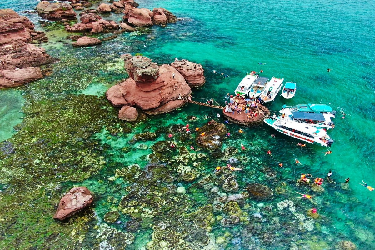 Colorful coral reef and snorkelers in turquoise water at Gam Ghi Island, Phu Quoc
