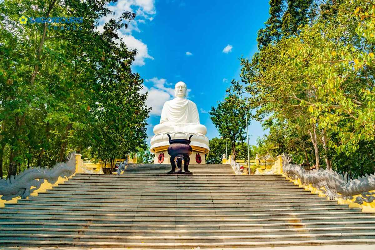 Steps leading to the White Buddha statue surrounded by trees at Long Son Pagoda in Nha Trang.